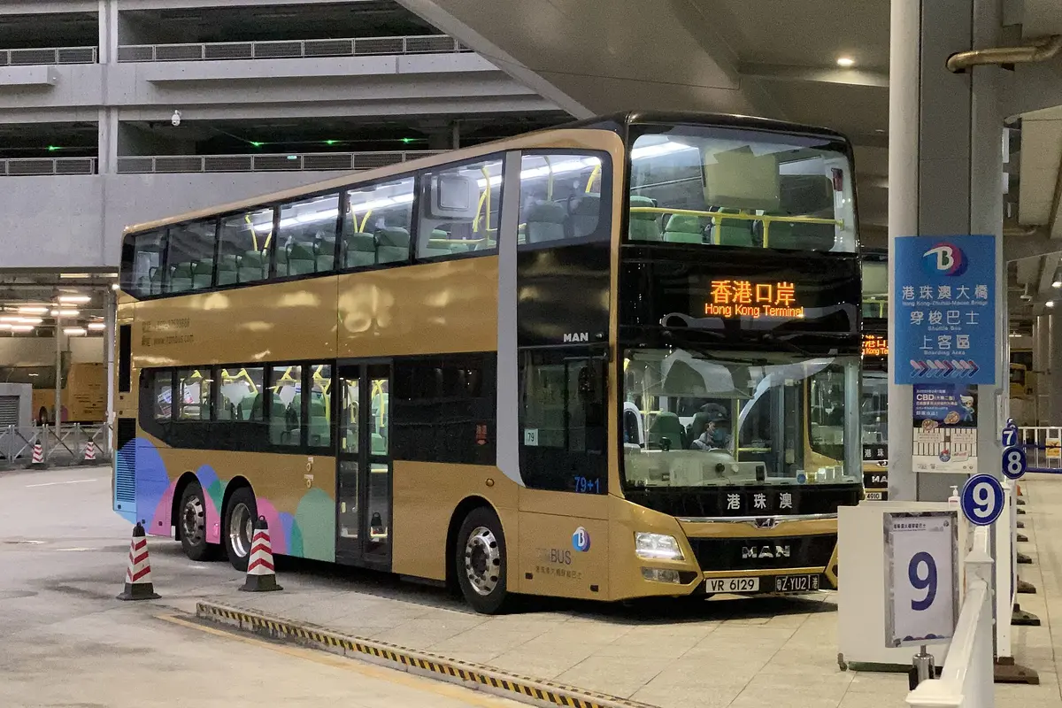 A gold double-decker bridge shuttle bus with the destination Hong Kong Terminal, parked at a numbered boarding bay
